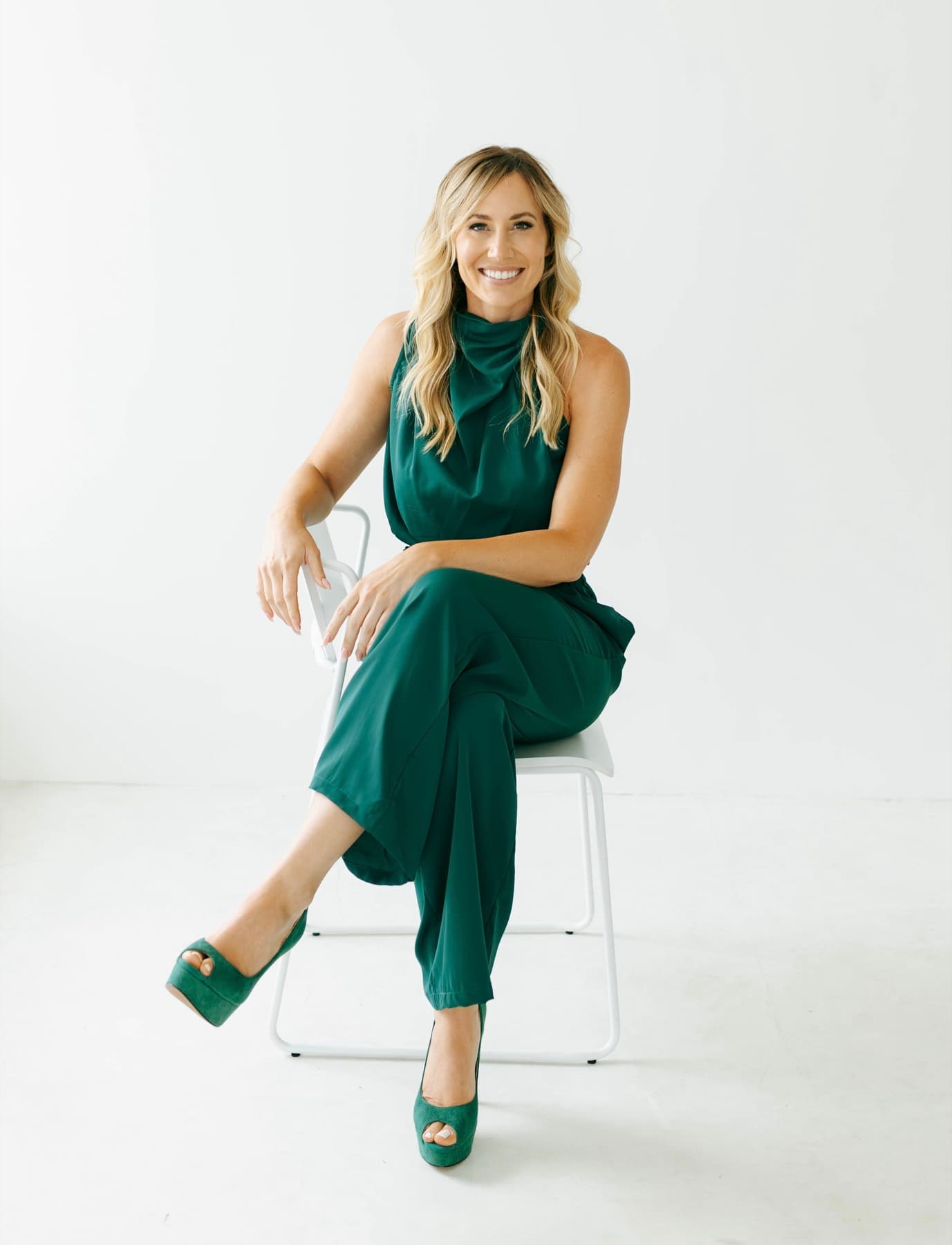 Brittney Diffiné, PA-C, seated, wearing an emerald green jumpsuit